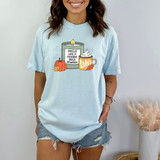 Smells Like A GG Rewatch DTF Heat Transfer, woman wearing a light blue T-shirt with a graphic of a candle, pumpkin, and coffee mug with the text 'Smells Like A Gilmore Girls Rewatch'.