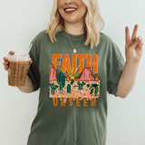 Faith Is Trusting The Unseen DTF Heat Transfer, a woman wearing a t-shirt with a colorful desert scene and inspirational text, holding a coffee drink and making a peace sign.