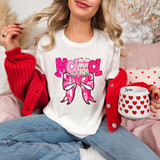 Mama Valentine Coquette DTF Heat Transfer, woman wearing a white t-shirt with a pink and purple bow design and colorful text, holding a mug with red hearts, cozy red sweater, and sitting on a pink sofa.
