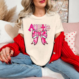 Auntie Valentine Coquette DTF Heat Transfer, pink and red graphic design of a bow with a heart and the word Auntie on a woman's white t-shirt.