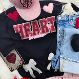 Heartbreaker Sequin Patch, close-up of a black sweatshirt with red rhinestone heart and silver bow patches, paired with casual blue jeans and pink and red plush hearts on display.