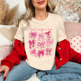 God Says I Am Pink Bows DTF Heat Transfer, a woman wearing a cream T-shirt with pink bow graphics and Bible verse references, styled with a red cardigan, jeans, and sitting in a cozy, decorated room.