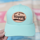 Don't Worry Be Happy Leather Hat Patch, a light blue baseball cap with a tan leather patch featuring the phrase 'Don't Worry Be Happy' in black text.