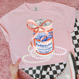 Bud Coquette Bow DTF Heat Transfer, pink T-shirt featuring a detailed graphic of a Budweiser beer can with a pink bow and pearl necklace, on a pink fuzzy background cut with a checkerboard pattern.