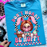 Don't Worry Be Hoppy Chuck DTF Heat Transfer, colorful design featuring a girl with bunny ears, sunglasses, and a basket of eggs on a blue t-shirt.