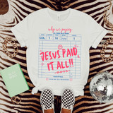 Jesus Paid It All! DTF Heat Transfer, product on a white T-shirt with pink text and design, surrounded by fashion accessories and a Bible.