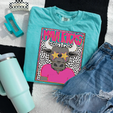 Mavericks Bull Colorful Mascot DTF Heat Transfer, vibrant graphic of a bull wearing pink shirt with star-shaped sunglasses on a turquoise t-shirt, with other fashion and crafting accessories around.