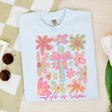 Faux Glitter He Is Risen Floral Cross DTF Heat Transfer, a white T-shirt with a colorful floral cross design and the words "He is risen" in pink.