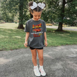 The Heavenly Race Hebrews 12:1 DTF Heat Transfer, a girl wearing a graphic T-shirt with a racing car design and biblical verse, standing outdoors on a park path.