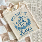 Run For The Roses DTF Heat Transfer, a beige T-shirt with a blue graphic of a jockey riding a horse surrounded by roses and text.