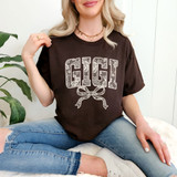 Gigi Faux Lace Coquette DTF Heat Transfer, fashion woman wearing a black T-shirt with floral lace design spelling GIGI and bow graphic, for custom clothing decoration.