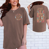 Life Is Better At The Beach SET DTF Heat Transfer, a colorful text design with a sun and flowers on a brown T-shirt.