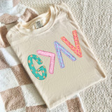 Patterned God is Greater than the Highs and Lows DTF Heat Transfer, colorful patterned applique design on a cream-colored t-shirt.