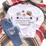 Hello Autumn Sublimation Transfer, a white sweatshirt with autumn-themed designs and text, featuring a pumpkin, a book, a coffee cup, a plaid blanket, and text that says 'Hello Autumn misty mornings, cozy crunchy leaves & nights, pumpkin spice!' placed on a multicolored striped blanket with a pair of ripped blue jeans.