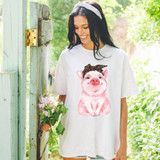 Bandana Piggy DTF Heat Transfer, a woman wearing a T-shirt with a cute pig graphic and a bandana, outdoor setting with greenery.
