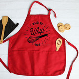 Watch Me Whip It FINAL STOCK Screen Print Transfer, red apron with whisk graphic and text, cooking utensils, and cookies on white background.