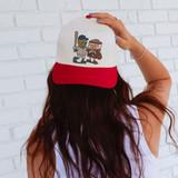 Peanut and Cracker Jack Character - PICK YOUR TEAM DTF Heat Transfer, person wearing a baseball cap with a Nut and Cracker Jack mascot design against a white brick wall background.