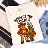 Respect Your Locals - PICK YOUR TEAM DTF Heat Transfer, product design featuring a cheerful cartoon character holding a sign that says Nebraska, surrounded by corn stalks.