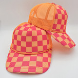 Neon Pink & Orange Checkered Foam Trucker Hat, vibrant trucker cap with mesh back and checkered pattern worn by a person.