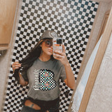 Pop Star Checker Mascot DTF Heat Transfer, person wearing a t-shirt with colorful star and checkered letter B design in front of a checkerboard background.