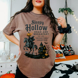Sleepy Hollow Dead And Breakfast DTF Heat Transfer, Halloween-themed T-shirt design featuring a haunted house, a black horse, pumpkins, and bats.