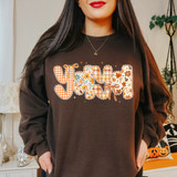 Fall Patterned Names DTF Heat Transfer, Christmas-themed multicolored alphabet letters with orange, white, and floral patterns on a woman's brown sweatshirt.