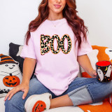 Leopard Boo DTF Heat Transfer, leopard print number 300 design on a pink T-shirt worn by a woman sitting with Halloween-themed cushions and slippers, holding a Halloween mug.