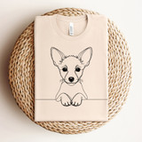 Dog Doodles DTF Heat Transfer, a minimalistic line art illustration of a cute puppy on a cream-colored t-shirt placed on a woven round placemat.