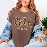 Fall Vibes Dark Floral DTF Heat Transfer, close-up of a woman wearing a brown sweatshirt with floral and pumpkin design with the words 'fall vibes'.