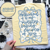 Motherhood Is My Ministry Raising Disciples Of Jesus SET DTF Heat Transfer, yellow fabric with floral design and handwritten-style message.