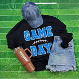 Game Day with Silicon Laces Patch - 10 Colors, sports-themed apparel and accessories, including a black sweatshirt with blue and white patch design, a denim cap, distressed denim shorts, and a brown thermos, all laid out on a green football field background.