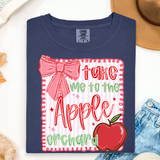 Take Me To The Apple Orchard DTF Heat Transfer, colorful design on a blue T-shirt featuring a pink bow, red and green text, and an apple graphic.