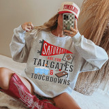 Red Saturdays Are For Tailgates & Touchdowns DTF Heat Transfer, woman in casual outfit wearing a sweatshirt with football-themed graphics and a red and white baseball cap, taking a mirror selfie.