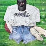 Comets Sequin Patch, sports-themed patch with football design on black baseball cap, placed on a casual outfit with a gray sweatshirt, denim shorts, white sneakers, and football on a green turf background.