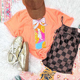 Alani-Style Citrus Drink Can Sequin Patch with Bow, decorative patch featuring a colorful slice of citrus fruit with a bow, on a coral T-shirt surrounded by checkered shorts, metallic shoes, and a brown cap.