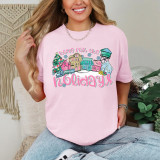 Preppy Home For The Holidays DTF Heat Transfer, colorful festive graphic of holiday houses, Christmas tree, and snowflakes on pink t-shirt.