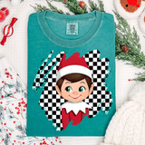 Red Elf Checker DTF Heat Transfer, cheerful elf cartoon wearing a Santa hat on a teal t-shirt with a checkered background and decorative holiday items around.