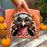 Turkey With Glasses DTF Heat Transfer, a colorful illustration of a turkey wearing stylish sunglasses, on a peach-colored fabric textile.