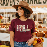 Boho Fall Vibes DTF Heat Transfer, woman wearing a maroon t-shirt with fall-themed letter design at an outdoor pumpkin market.