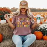 Pumpkin Pie & Family Drama Pattern DTF Heat Transfer, woman wearing a graphic T-shirt with a festive pumpkin pattern and text, in an autumn pumpkin patch setting with pumpkins and flowers.
