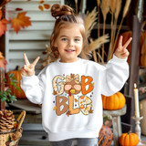 Girly Gobble DTF Heat Transfer, a young girl wearing a festive sweatshirt with autumn-themed letters and graphics.