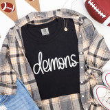 Demons White PUFF Transfer, white neon-style lettering on a black T-shirt with a plaid shirt and casual sneakers.