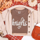 Knights White PUFF Transfer, image of a brown T-shirt with the word 'knights' printed on it, laid on a fall-themed background with leaves, a cardigan, a pumpkin, and a handbag.