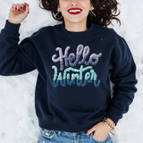 Faux Latch Hook Hello Winter DTF Heat Transfer, a woman wearing a navy sweatshirt with a colorful latch hook style design that says 'Hello Winter' in a cozy winter theme.