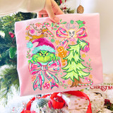 Product Bow Green Guy Collage DTF Heat Transfer, colorful Christmas-themed design on pink fabric featuring Grinch with a Santa hat, a Christmas tree, gingerbread man, and holiday decorations.