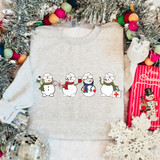 Nurse Snowman DTF Heat Transfer, festive design of four snowmen dressed as nurses with medical accessories, on a gray sweatshirt surrounded by Christmas decorations.