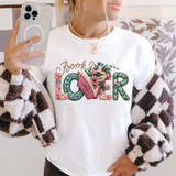 Faux Yarn Book Lover DTF Heat Transfer, colorful embroidered yarn design on a white T-shirt featuring the word 'love' with floral and leaf accents.