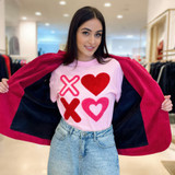 XOXO Fluffy Valentine's Day Patch, a woman wearing a pink T-shirt with red and pink heart and X patches and holding a red jacket open inside a clothing store.