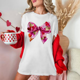 Faux Painted Heart Bow DTF Heat Transfer, vibrant pink and gold heart-patterned bow design on a white t-shirt.