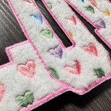 LOVE Multicolor Heart Fluffy Valentine's Day Patch, close-up of colorful embroidered hearts on a soft fluffy white fabric with pink border edge.